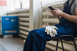 A man sits in a basement with gloves resting on his knees after sewer line repair in Jackson County.