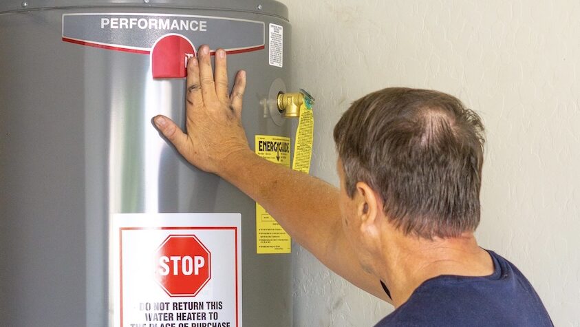 A homeowner touches a new industrial sized unit after opting for a replacement instead of more water heater repairs in Lee's Summit.