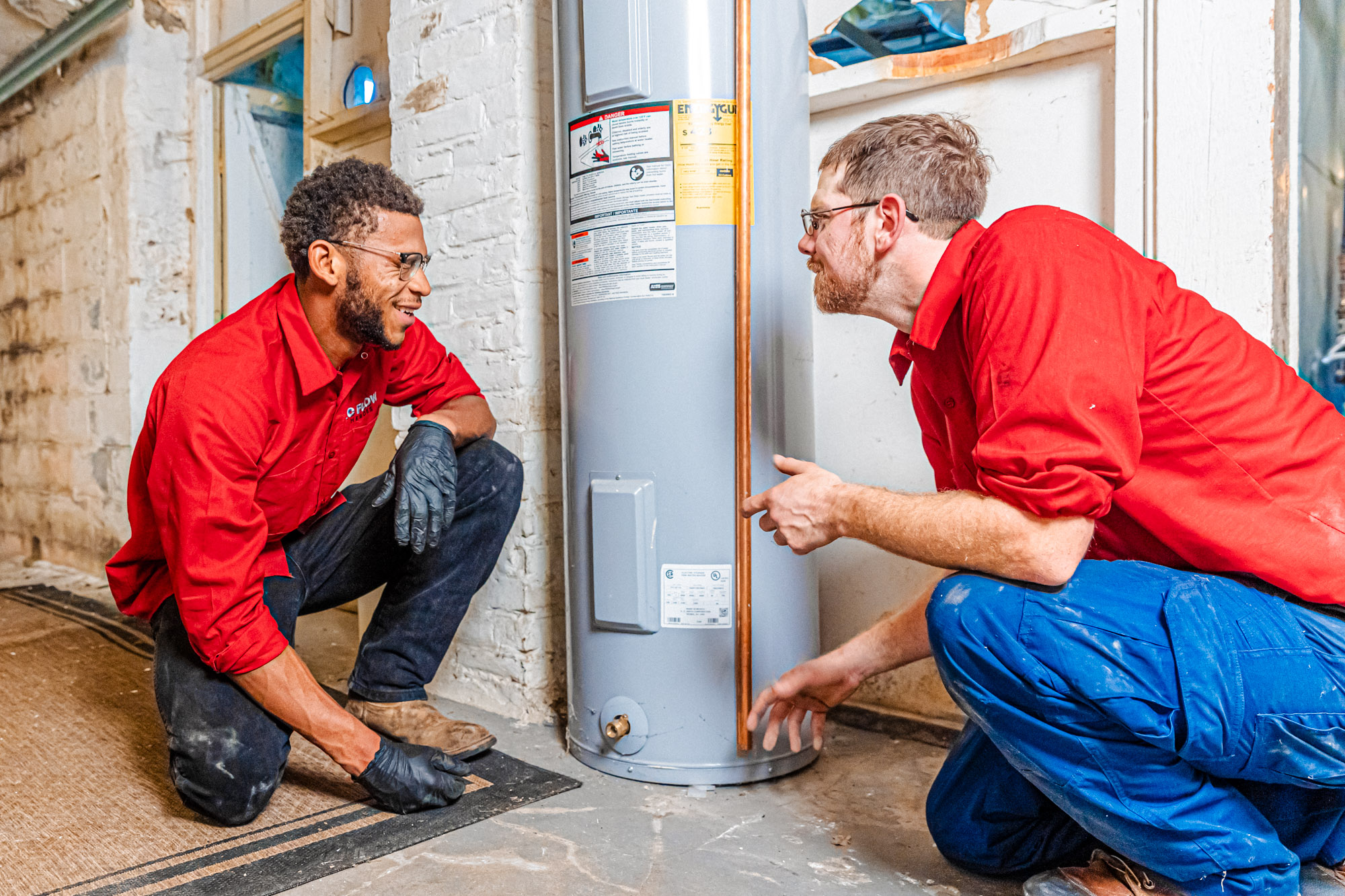 Two emergency plumbers in Jackson County address a client's water heater leak.
